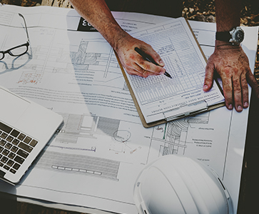 Contremaître qui vérifie un rapport avec des plans en dessous sur un chantier
