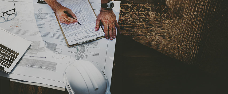Contremaître qui vérifie un rapport avec des plans en dessous sur un chantier